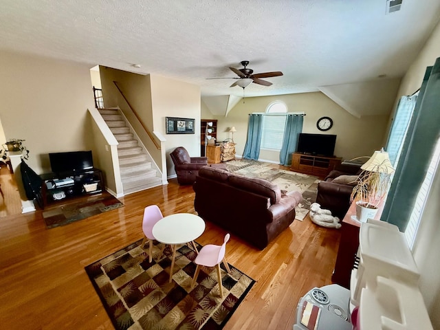 living area featuring stairway, a ceiling fan, a textured ceiling, and wood finished floors