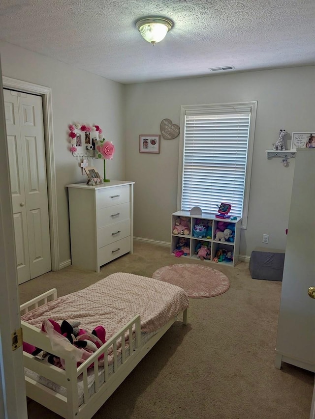 bedroom with light colored carpet, a textured ceiling, and visible vents