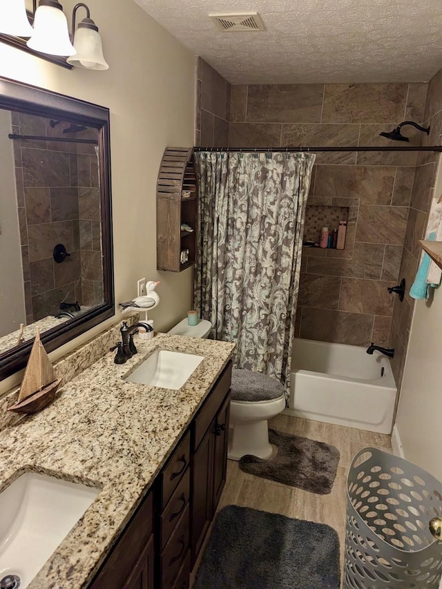 full bathroom with visible vents, shower / tub combo with curtain, wood finished floors, a textured ceiling, and a sink