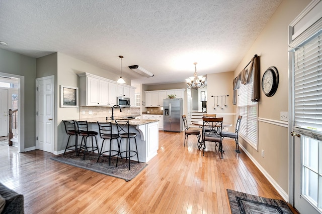 116 N Wynridge Way, Goodlettsville, TN 37072 - kitchen featuring stainless steel appliances, a peninsula, a chandelier, healthy amount of natural light, and a textured ceiling