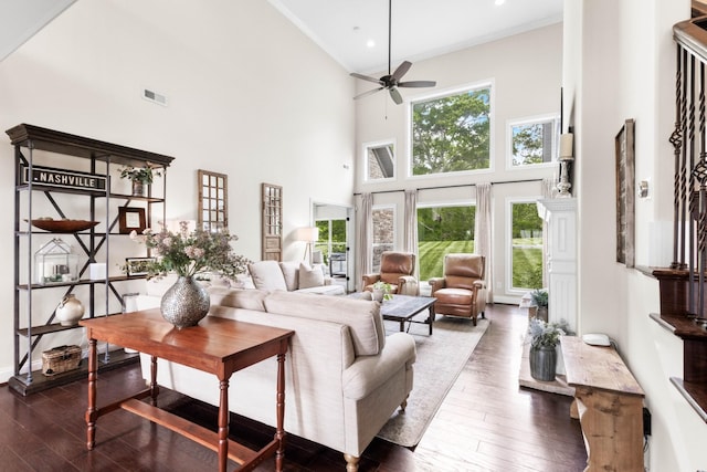 living area featuring visible vents, crown molding, ceiling fan, a high ceiling, and dark wood-type flooring