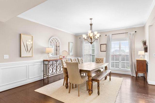 dining space with an inviting chandelier, ornamental molding, a wainscoted wall, and hardwood / wood-style floors