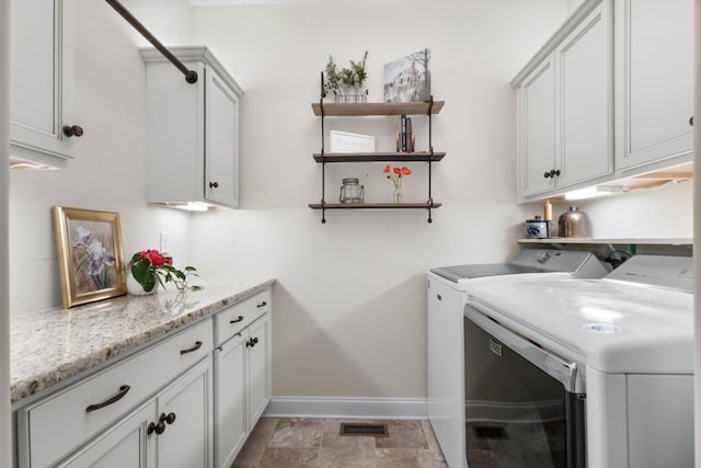 laundry area with baseboards, cabinet space, washing machine and dryer, and visible vents