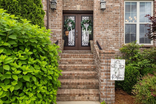 property entrance featuring french doors and brick siding