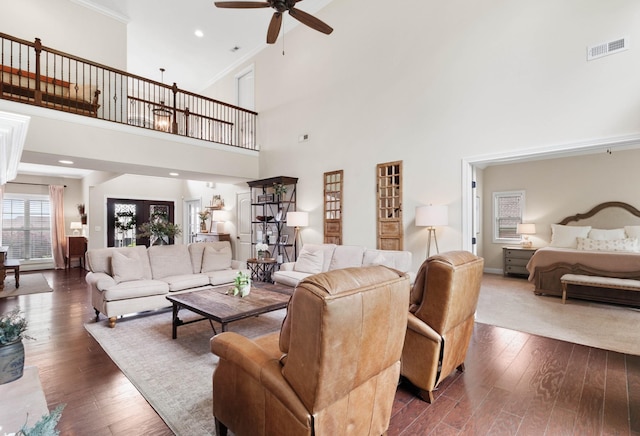 living room featuring a high ceiling, a ceiling fan, dark wood-style floors, and visible vents