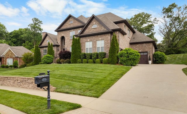 french country home featuring concrete driveway, brick siding, an attached garage, and a front lawn