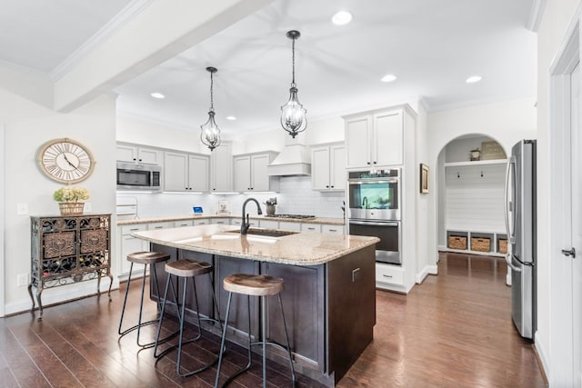 kitchen with backsplash, dark wood-style flooring, appliances with stainless steel finishes, a sink, and an island with sink