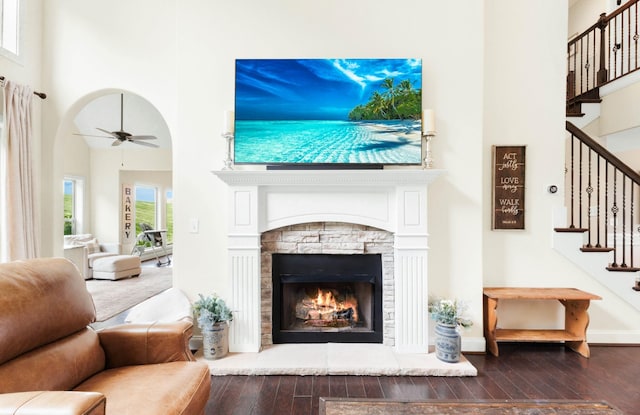 living area with stairway, a fireplace, hardwood / wood-style flooring, and a towering ceiling