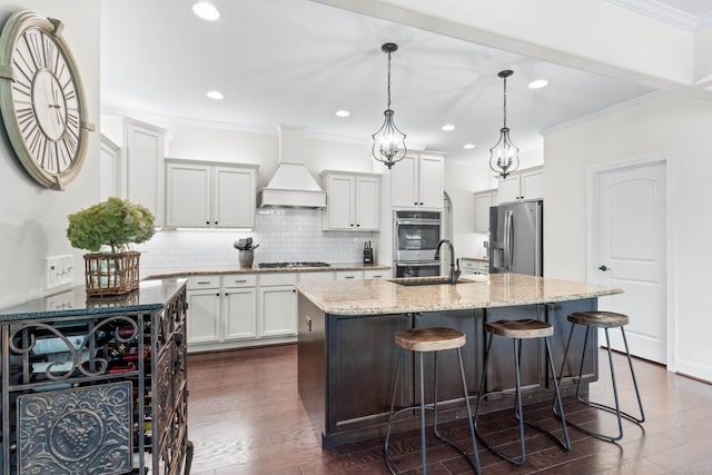 kitchen with tasteful backsplash, light stone countertops, custom range hood, a sink, and stainless steel appliances