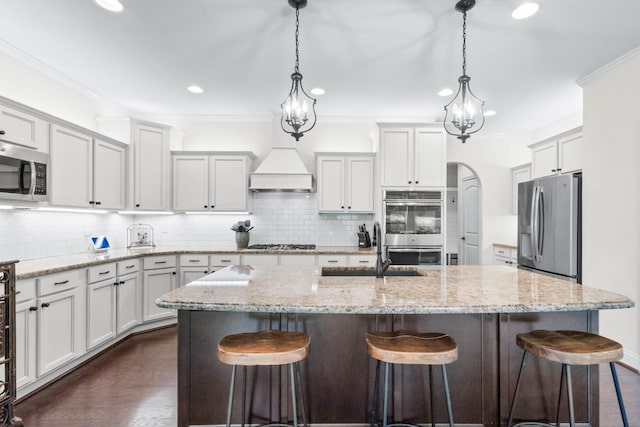 kitchen featuring a sink, appliances with stainless steel finishes, a kitchen breakfast bar, and custom exhaust hood