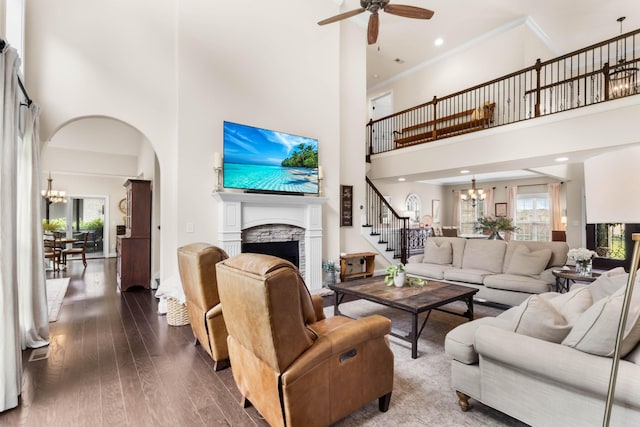 living area featuring ceiling fan with notable chandelier, a high ceiling, a wealth of natural light, and stairway