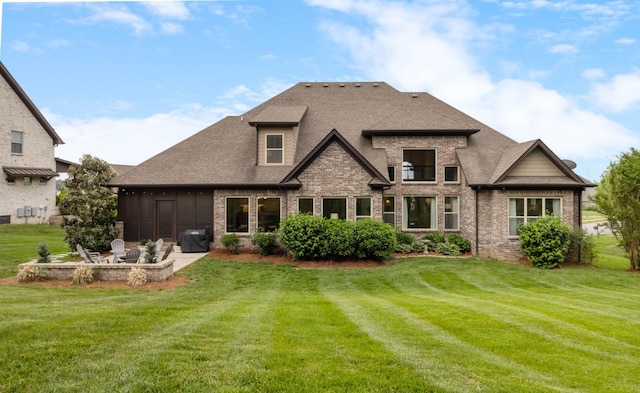 rear view of house with a lawn, brick siding, a patio area, and roof with shingles