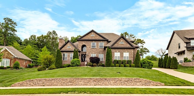 view of front of home with brick siding, a chimney, and a front lawn