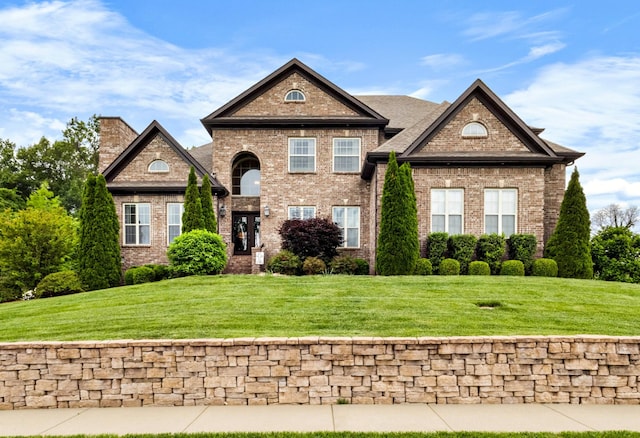 view of front of home featuring a chimney, a front lawn, and brick siding