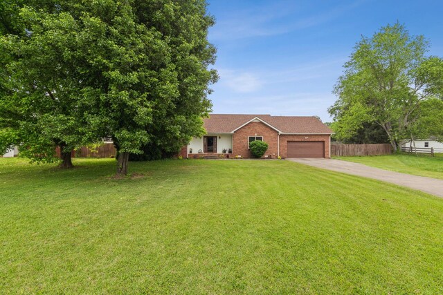 view of front facade with driveway, brick siding, fence, a front lawn, and an attached garage