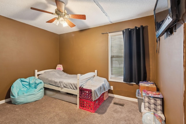 carpeted bedroom with a textured ceiling, ceiling fan, visible vents, and baseboards