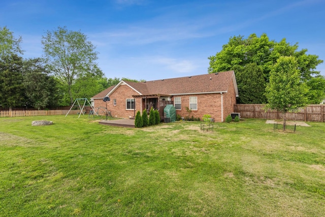 rear view of house featuring brick siding, a fenced backyard, and a yard
