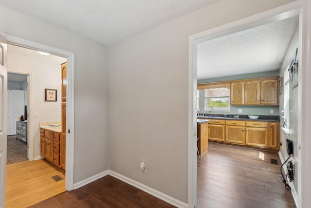 kitchen with visible vents, dark countertops, brown cabinets, baseboards, and wood-type flooring
