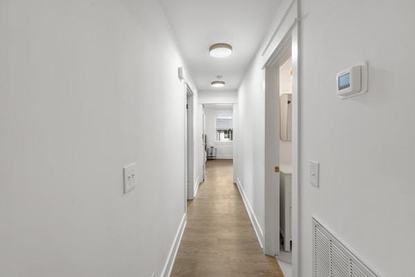 hallway with visible vents, baseboards, and wood finished floors