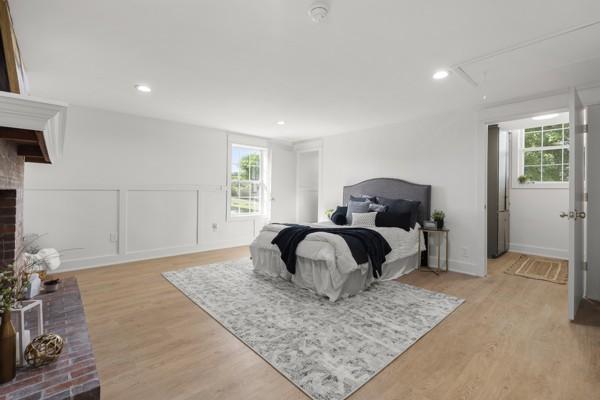 bedroom featuring a fireplace, attic access, recessed lighting, and light wood-style flooring