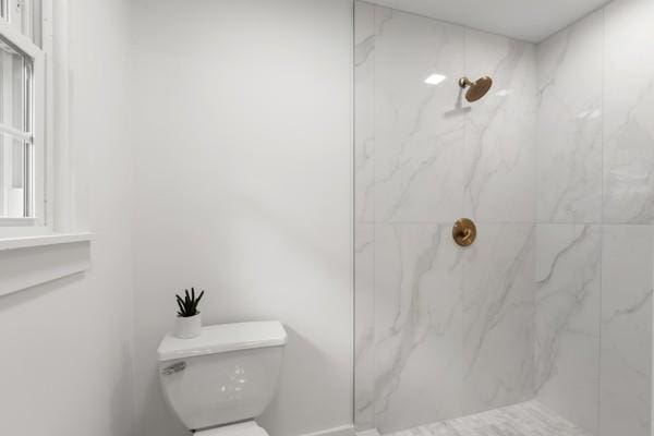 full bathroom with toilet and a marble finish shower