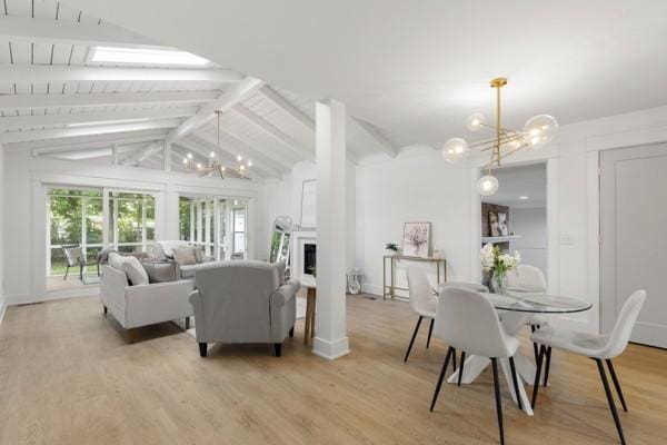 living room featuring a fireplace, an inviting chandelier, vaulted ceiling with beams, and light wood-type flooring