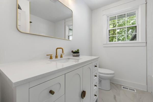full bathroom featuring vanity, visible vents, marble finish floor, toilet, and baseboards