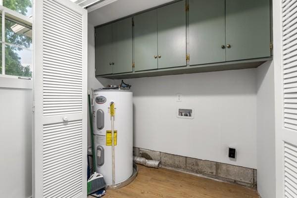 washroom featuring wood finished floors, cabinet space, and electric water heater