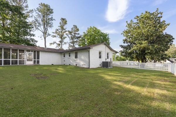 back of house with a lawn, a fenced backyard, a sunroom, and cooling unit
