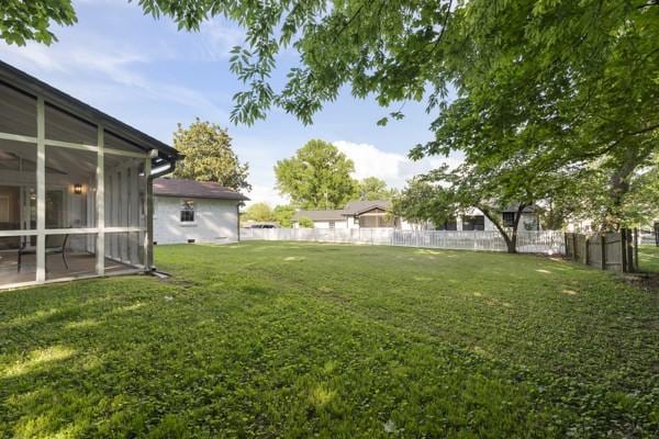 view of yard with fence and a sunroom