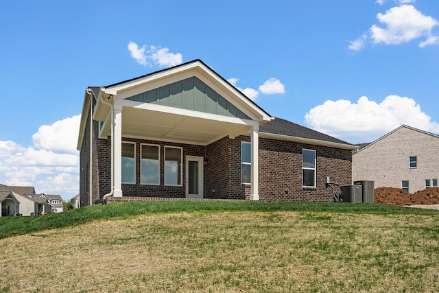 rear view of property featuring brick siding, board and batten siding, central air condition unit, and a yard