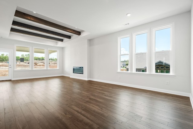 unfurnished living room featuring visible vents, a glass covered fireplace, beamed ceiling, baseboards, and dark wood-type flooring