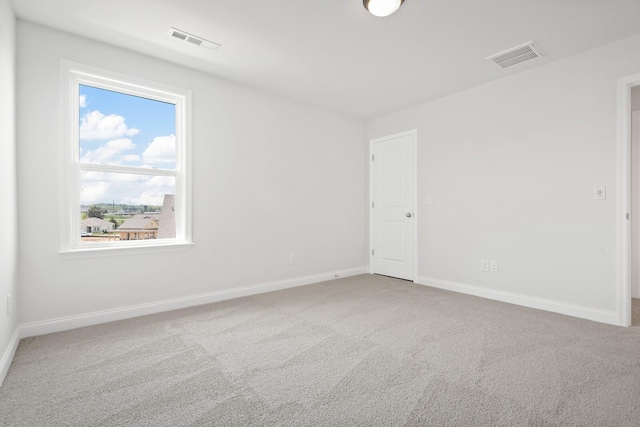 carpeted spare room featuring baseboards and visible vents