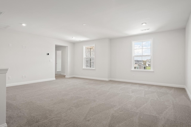spare room with baseboards, recessed lighting, and light carpet