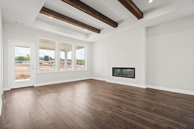 unfurnished living room with visible vents, dark wood-style flooring, a glass covered fireplace, beam ceiling, and baseboards