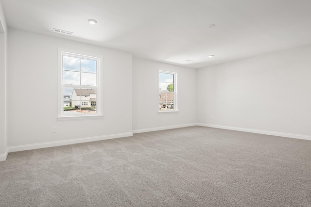 empty room with carpet flooring, baseboards, and visible vents