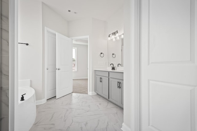 full bathroom featuring vanity, marble finish floor, baseboards, visible vents, and a soaking tub