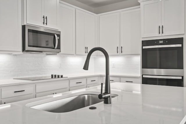 kitchen featuring stainless steel microwave, white cabinetry, double wall oven, and black electric cooktop