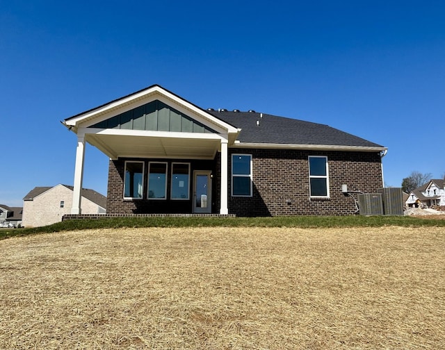 rear view of house with brick siding, board and batten siding, and covered porch
