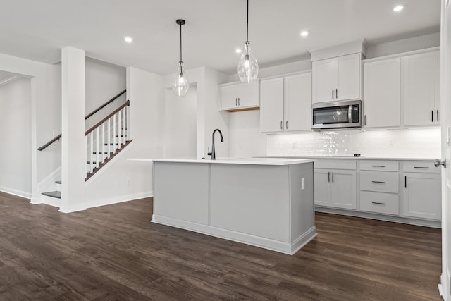 kitchen with recessed lighting, dark wood finished floors, stainless steel microwave, and tasteful backsplash
