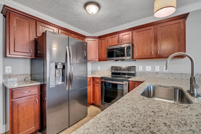 kitchen with light stone counters, a sink, a textured ceiling, and stainless steel appliances