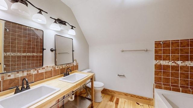full bath featuring a sink, tasteful backsplash, toilet, and lofted ceiling