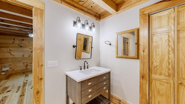 bathroom featuring beam ceiling, wooden ceiling, wood finished floors, and vanity