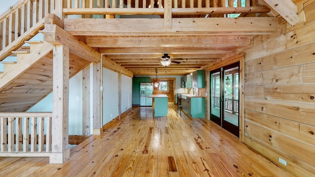 interior space with light wood-type flooring, a ceiling fan, and beamed ceiling