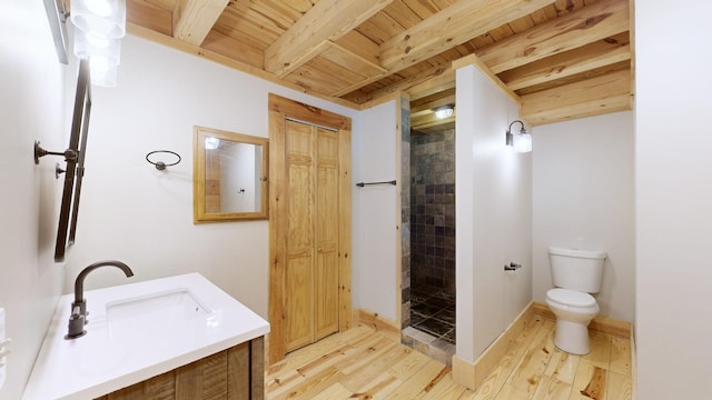 full bath featuring a tile shower, a sink, toilet, wooden ceiling, and wood finished floors