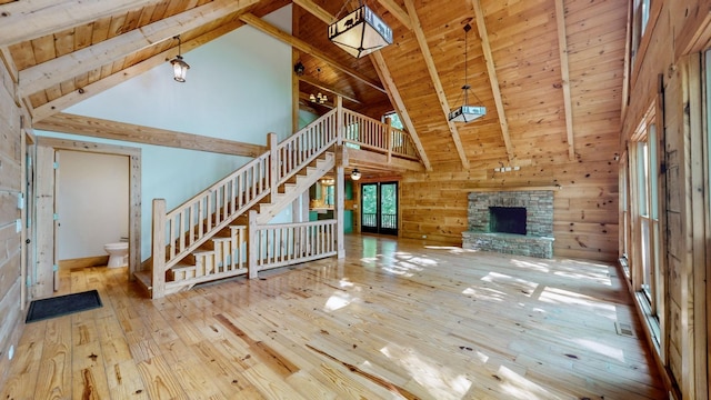 unfurnished living room featuring hardwood / wood-style floors, wooden walls, high vaulted ceiling, wood ceiling, and a ceiling fan