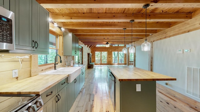kitchen with a sink, butcher block countertops, light wood-type flooring, a kitchen island, and beamed ceiling