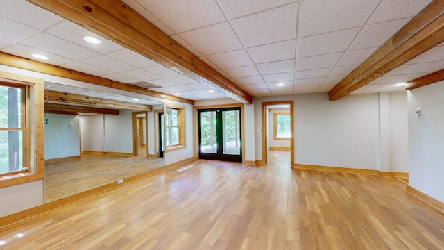 unfurnished living room featuring baseboards, recessed lighting, a drop ceiling, and light wood-type flooring