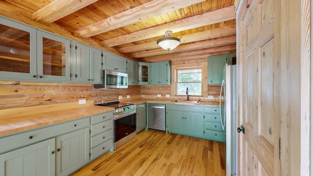 kitchen with beamed ceiling, wood ceiling, a sink, light wood-style flooring, and stainless steel appliances