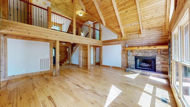 unfurnished living room with visible vents, a stone fireplace, high vaulted ceiling, stairway, and wood ceiling